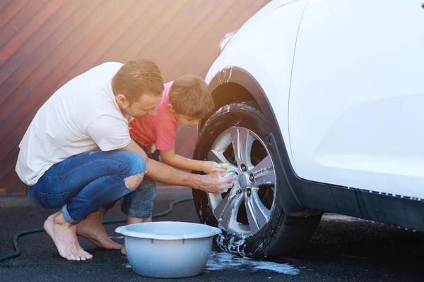 Vinculándose por sus días de lavado de autos. Largura completa de un padre y un hijo lavando la rueda de un coche juntos. — Foto de Stock