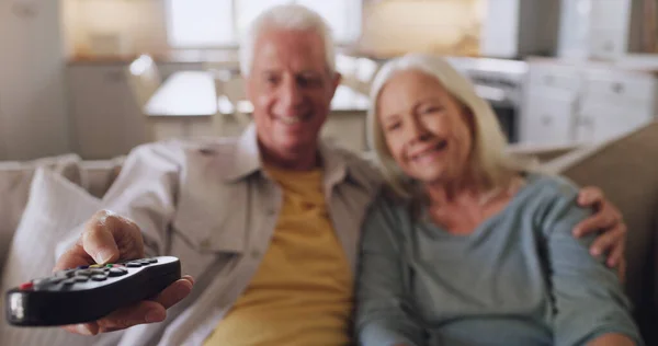 ¿Qué deberíamos ver? Fotografía de una pareja de ancianos sentados en el sofá juntos en casa y viendo la televisión. — Foto de Stock