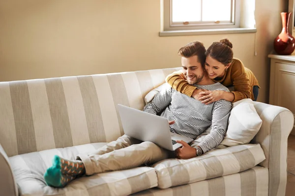 Laisse-moi voir de quoi tu ris... Prise de vue d'un jeune couple utilisant un ordinateur portable tout en se relaxant à la maison. — Photo