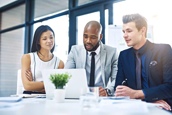 Erfolg ist das Produkt von Teamarbeit. Schnappschuss einer Gruppe junger Geschäftsleute bei einer Diskussion mit einem Laptop in einem modernen Büro. — Stockfoto