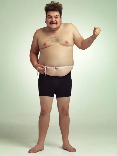Gå ner i vikt och må bra. Skjuten av en överviktig man som mäter sig själv. — Stockfoto