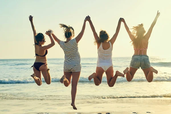 Les jours de plage sont les meilleurs. Vue arrière prise de femmes meilleures amies sautant dans les airs à la plage. — Photo