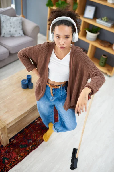 Im waiting for the next song to start before cleaning again. Shot of a woman wearing headphones while busy cleaning at home. — Stock Photo, Image