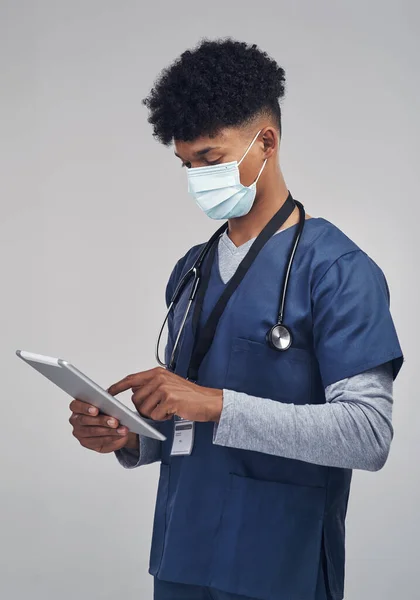 Indossare la maschera, è buono per i numeri. Scatto di un infermiere con una tavoletta digitale in piedi su uno sfondo grigio. — Foto Stock
