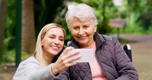 Smile mom. Cropped shot of a cheerful elderly woman and her daughter taking a self portrait together outside in a park. — Stock Photo, Image