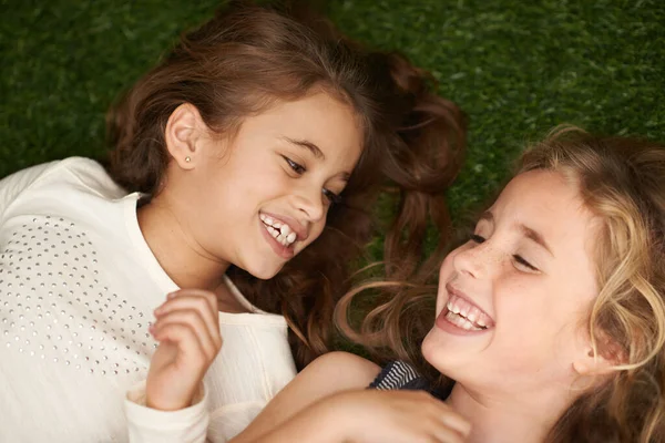 Pure childhood delight. Cropped shot of two little girls lying on their backs outside. — ストック写真