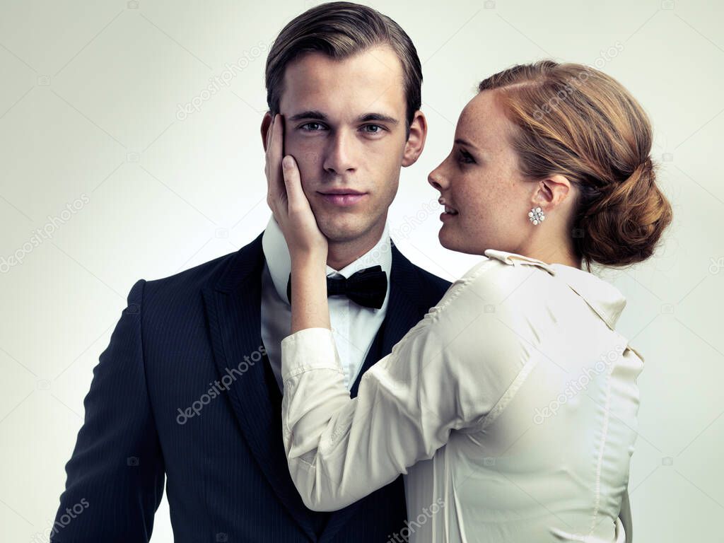 He makes them weak at the knees. A cropped studio portrait of a dapper young man with a beautiful girl on his arm.