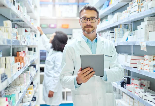 É um melhor amigo dos farmacêuticos. Tiro de um homem maduro usando um tablet digital para fazer inventário em uma farmácia. — Fotografia de Stock