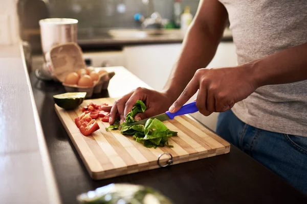 Asegúrate de que tus comidas tengan suficientes verduras. Recorte de un hombre irreconocible picando verduras mientras hace una comida en su cocina en casa. — Foto de Stock