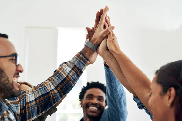 Teamwork voor de overwinning. Opname van een groep collega 's die elkaar een high five geven in een modern kantoor. — Stockfoto