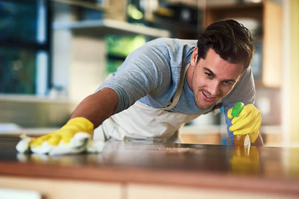 A cozinha em breve será espumante limpo e impecável. Tiro cortado de um jovem limpando uma superfície de cozinha em casa. — Fotografia de Stock