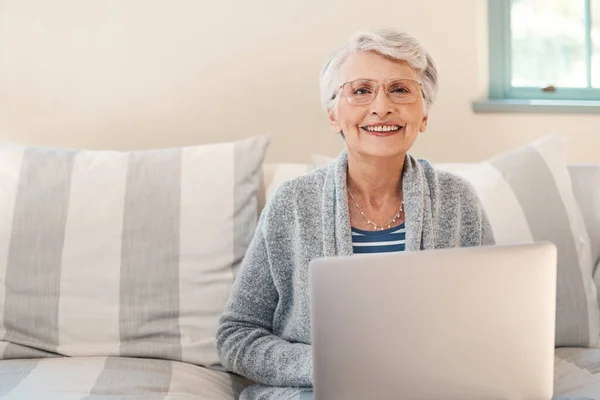 Veruit de makkelijkste manier om op de hoogte te blijven. Foto van een oudere vrouw met behulp van een laptop op de bank thuis. — Stockfoto