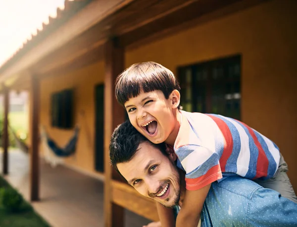 My dva se tak bavíme. Oříznutý portrét láskyplného mladého otce prasečinec jeho malého syna, zatímco stojí na jejich dvorku doma. — Stock fotografie