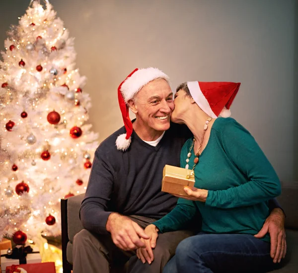 Het is zeker leuker om te geven. Een gelukkig volwassen stel wisselt kerstcadeaus uit voor hun kerstboom. — Stockfoto