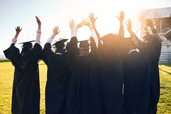 Celebrando cálidos recuerdos y grandes sueños para el futuro. Imagen retrospectiva de un grupo de estudiantes en fila con los brazos levantados el día de la graduación. —  Fotos de Stock