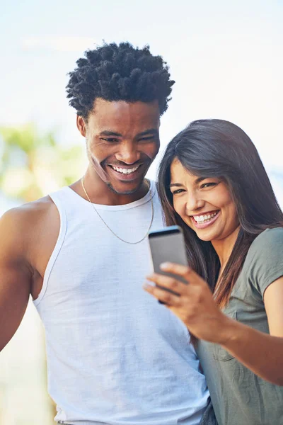Ett par profilbilder. Skjuten av ett lyckligt ungt par som använder en mobiltelefon tillsammans. — Stockfoto
