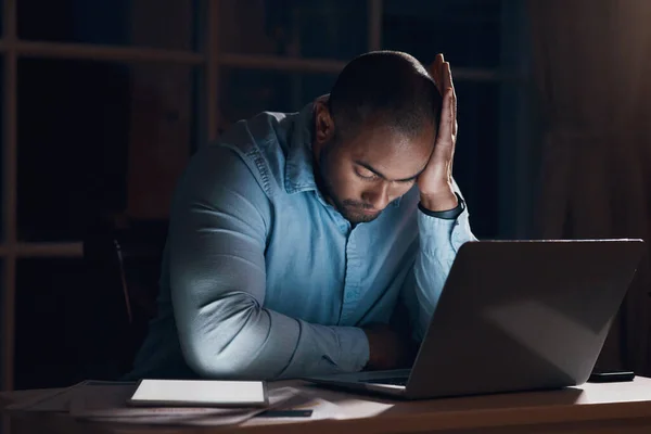 Os negócios podem ser desafiadores. Tiro de um jovem empresário olhando estressado enquanto trabalhava em seu laptop tarde da noite. — Fotografia de Stock