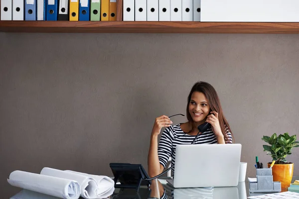 Clientes felizes por todo o lado. Uma jovem empresária conversando ao telefone enquanto se senta em sua mesa de escritório. — Fotografia de Stock