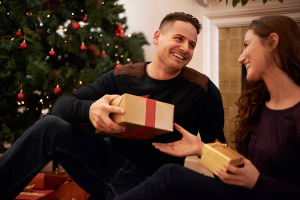 Najlepszym prezentem wokół drzewa jest miłość. Szczęśliwa młoda para otwiera prezenty w Boże Narodzenie. — Zdjęcie stockowe