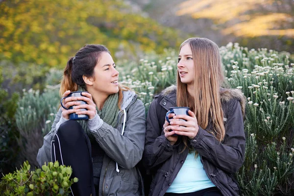 Нравится кофе. Выстрел двух привлекательных молодых женщин, наслаждающихся горячими напитками во время похода. — стоковое фото