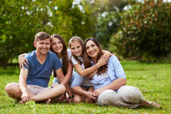 Vi voglio tanto bene, ragazzi. Ritratto di una giovane famiglia allegra seduta in un parco insieme durante il giorno. — Foto Stock