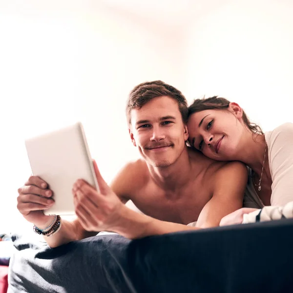 Łączy nas silna więź. Portret młodej pary spędzającej leniwy dzień w łóżku z tabletem. — Zdjęcie stockowe