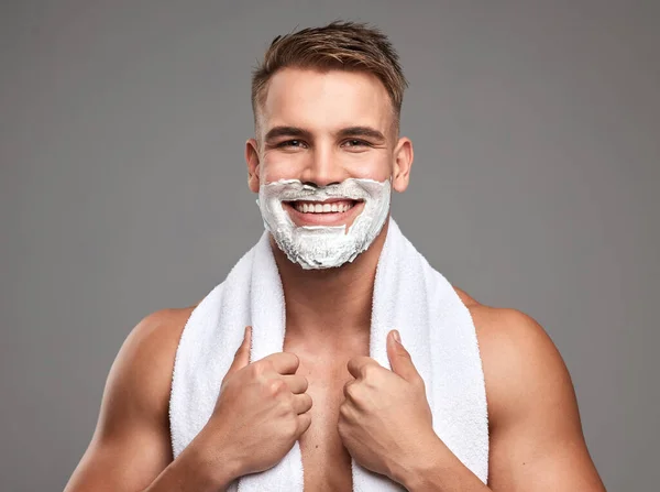 Gotta look good for my date. Studio shot of a handsome young man with shaving foam on his beard against a grey background. — Stock Photo, Image