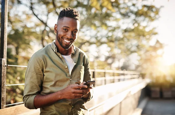 Me encantan los mensajes. Retrato recortado de un joven guapo usando su teléfono celular mientras estaba afuera. —  Fotos de Stock