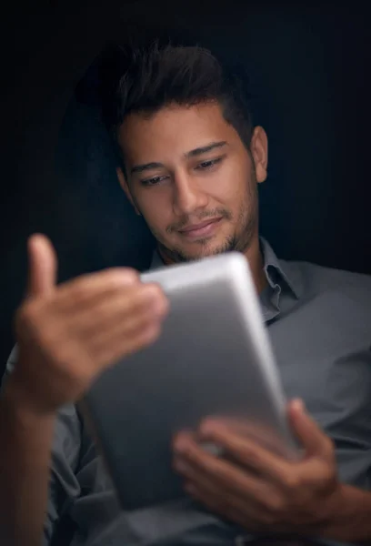 Se trata de hacer que la tecnología funcione para ti. Recorte de un joven usando su tableta por la noche. —  Fotos de Stock