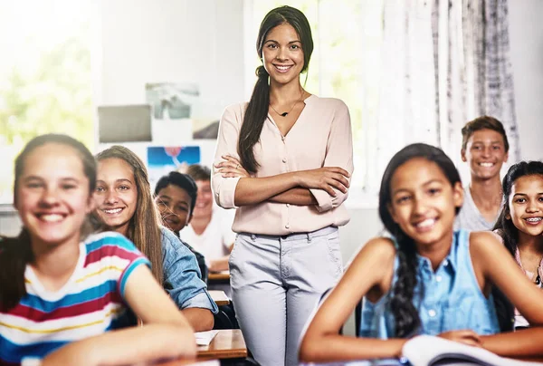 Ihre Lieblingsklasse mit ihrem Lieblingslehrer. Porträt einer attraktiven jungen Lehrerin, die mit verschränkten Armen in einem Klassenzimmer steht. — Stockfoto