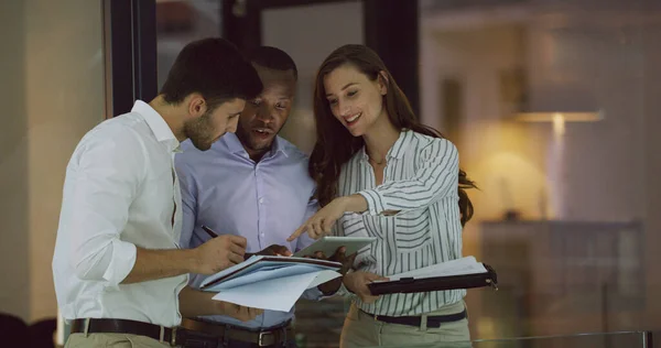 Theyll all get a chance to give input. Cropped shot of three businesspeople looking over a tablet while standing in the office lobby. — ストック写真