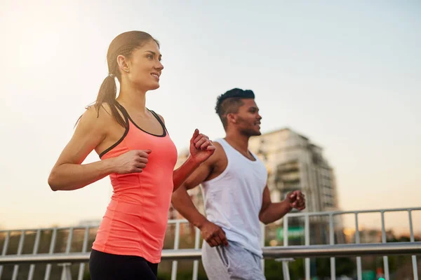 Enjoying their morning run. Shot of a young couple crossing a bridge during their run. — Stock Photo, Image