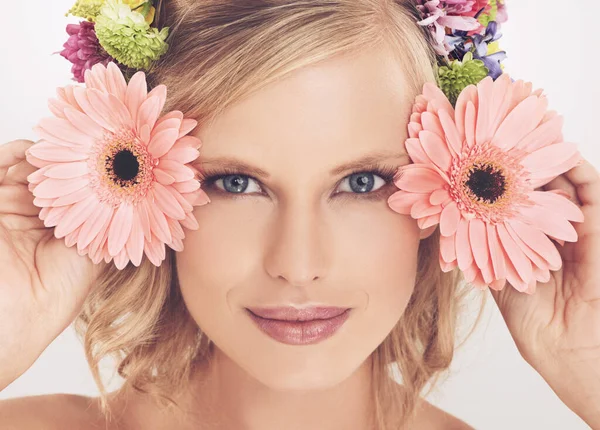 Kukkakaunotar. Nuori nainen kukka-asetelma hiuksissaan hymyilee kameralle. — kuvapankkivalokuva