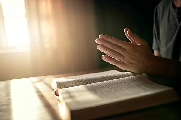 Beginnt seinen Tag auf die richtige Weise. Schnappschuss eines nicht identifizierbaren Mannes, der seine Hände im Gebet über einer offenen Bibel umklammert. — Stockfoto