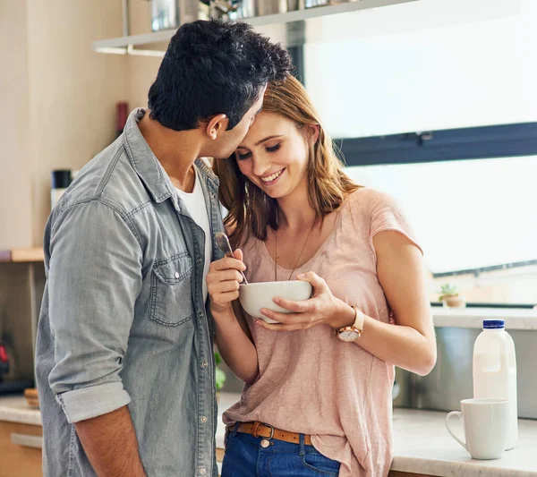 Profiter de la nourriture... et des baisers. Tourné d'un jeune couple affectueux debout dans leur cuisine. — Photo