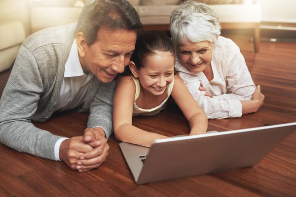 Kinderen van vandaag zijn zo technisch onderlegd. Een foto van een klein meisje die haar grootouders iets liet zien op een laptop.. — Stockfoto