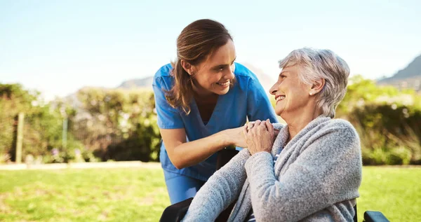 Wat vitamine D is precies wat je vandaag nodig hebt. Gesneden schot van een jonge vrouwelijke verpleegster buiten met een senior patiënt in een rolstoel. — Stockfoto