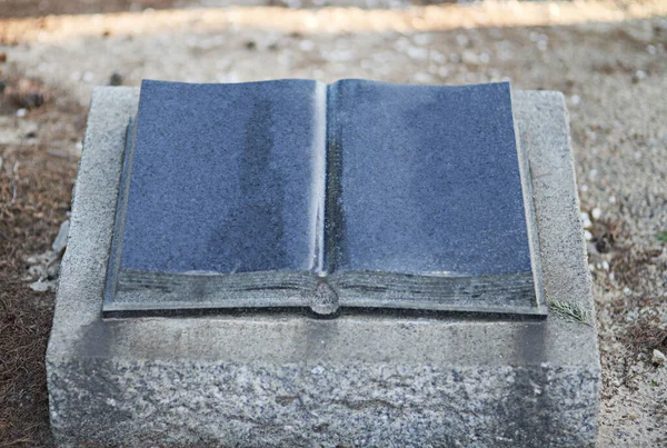 The holy book will forever be with them. Shot of a gravestone in a cemetery. — Stock Photo, Image