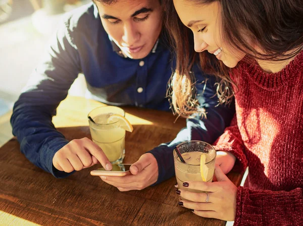 Primeras fechas en la edad de la aplicación. Fotografía de un joven y una mujer usando un teléfono móvil juntos en una cita en una cafetería. —  Fotos de Stock