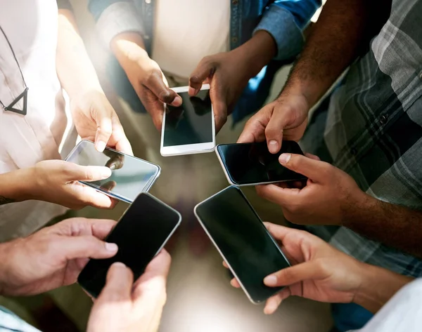 Einfach auf Senden drücken. Schnappschuss einer Gruppe Kollegen, die ihr Handy benutzen, während sie im Kreis stehen. — Stockfoto