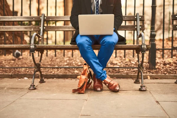 Quando o escritório não chega. Tiro de um homem irreconhecível trabalhando em seu laptop enquanto estava sentado em um banco fora durante o dia. — Fotografia de Stock
