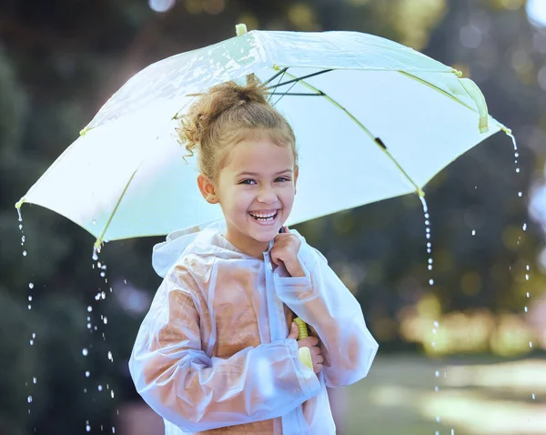 Ideje egy kis csínytevésnek. Lelőttek egy kislányt, aki játékosan állt az esőben az esernyőjével a kezében.. — Stock Fotó
