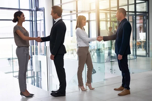 Samen streven naar meer kansen. Schot van een groep zakenmensen die elkaar de hand schudden in een kantoor. — Stockfoto