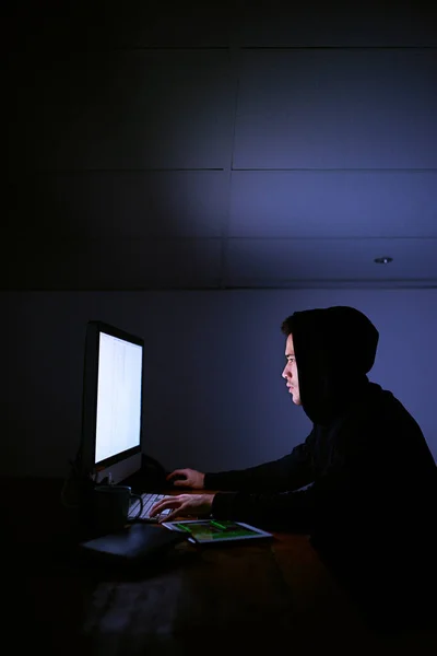 为他的下一个受害者在网上打滚在黑暗中使用计算机对蒙面计算机黑客开枪. — 图库照片