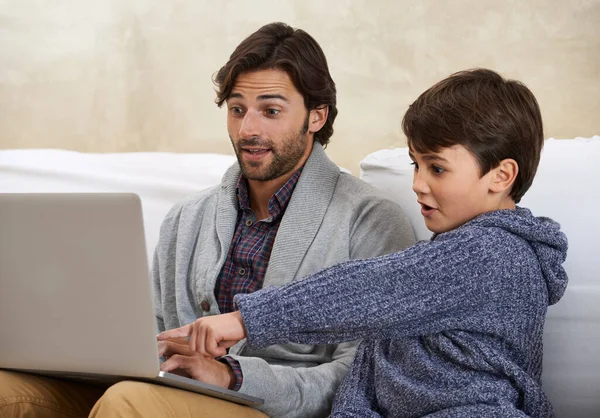 Spójrz na tę nową grę, tato. Młody chłopiec i jego ojciec bawią się na laptopie. — Zdjęcie stockowe