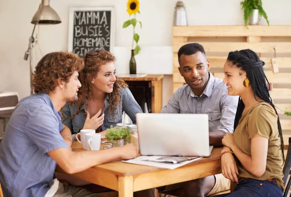 Ils s'amusent à discuter. Un groupe d'amis assis ensemble dans un café avec un ordinateur portable. — Photo