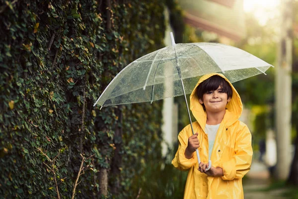 Ανυπομονώ για το ουράνιο τόξο μετά τη βροχή. Τραβηγμένο πλάνο ενός αξιολάτρευτου μικρού αγοριού στη βροχή έξω. — Φωτογραφία Αρχείου