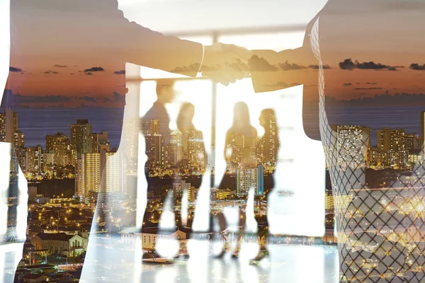 Business in the bustle of the city. Shot of a city at sunset superimposed over businesspeople shaking hands in the boardroom. — ストック写真