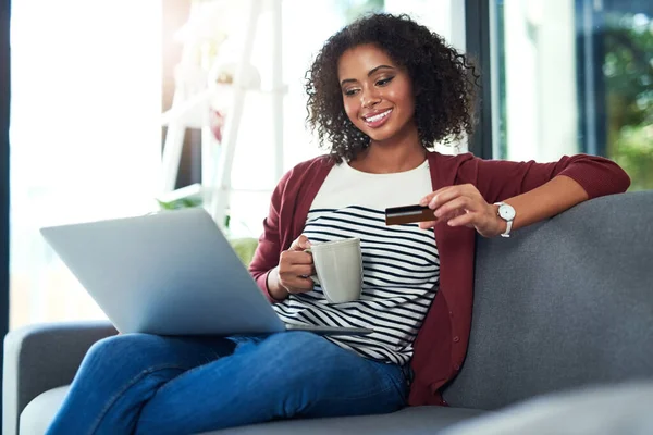 Moi, le temps c'est traiter le temps. Prise de vue d'une jeune femme utilisant un ordinateur portable et une carte de crédit sur le canapé à la maison. — Photo