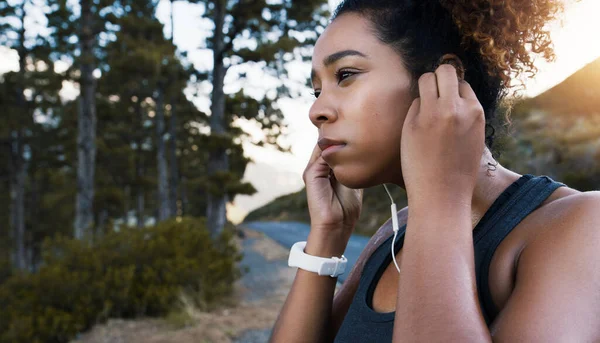 Συνδέθηκα και είμαι έτοιμος να τρέξω. Φωτογραφία μιας νεαρής αθλητικής γυναίκας που ακούει μουσική ενώ γυμνάζεται σε εξωτερικούς χώρους. — Φωτογραφία Αρχείου